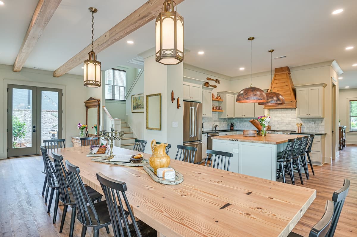 The Wilson House kitchen and dining area with farmhouse table, exposed beams, and copper pendant lights